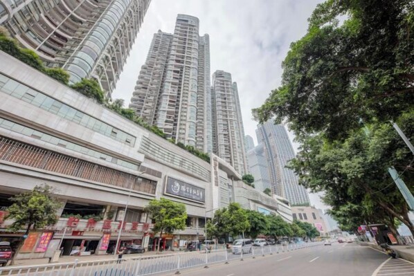 A city street with high-rise buildings, a pedestrian walkway, and a clear sky.