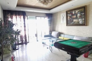A living room with a billiards table, a sofa, a potted plant, and a painting on the wall. - Meitu Apartment Hotel (Chongqing Jiefangbei Chaotianmen Branch) (Chongqing)