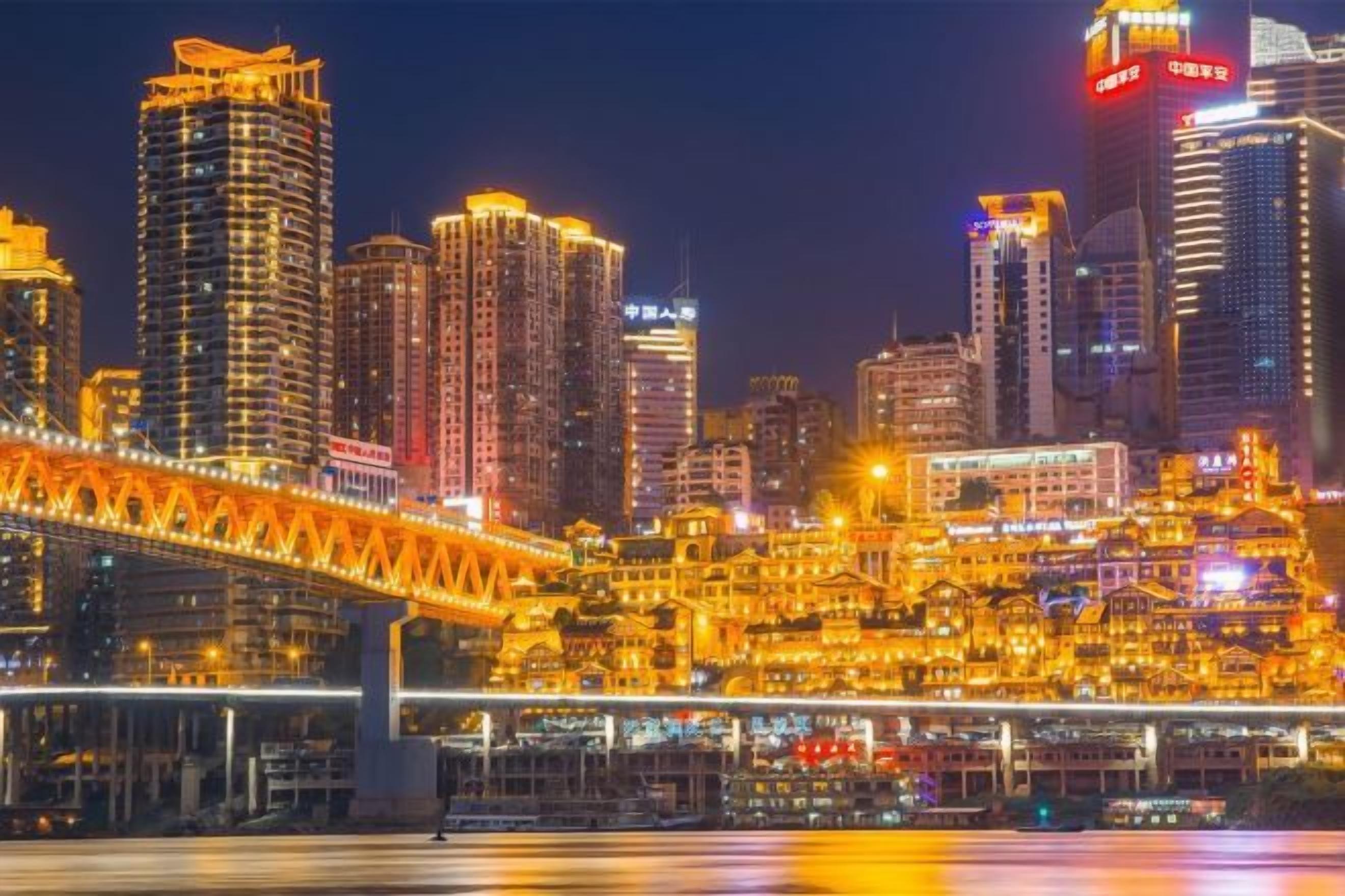 A cityscape with illuminated buildings and a bridge.