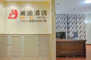 A hotel reception area with a wooden desk, a computer, and a wall-mounted TV. - Meitu Apartment Hotel (Chongqing Jiefangbei Chaotianmen Branch) (Chongqing)