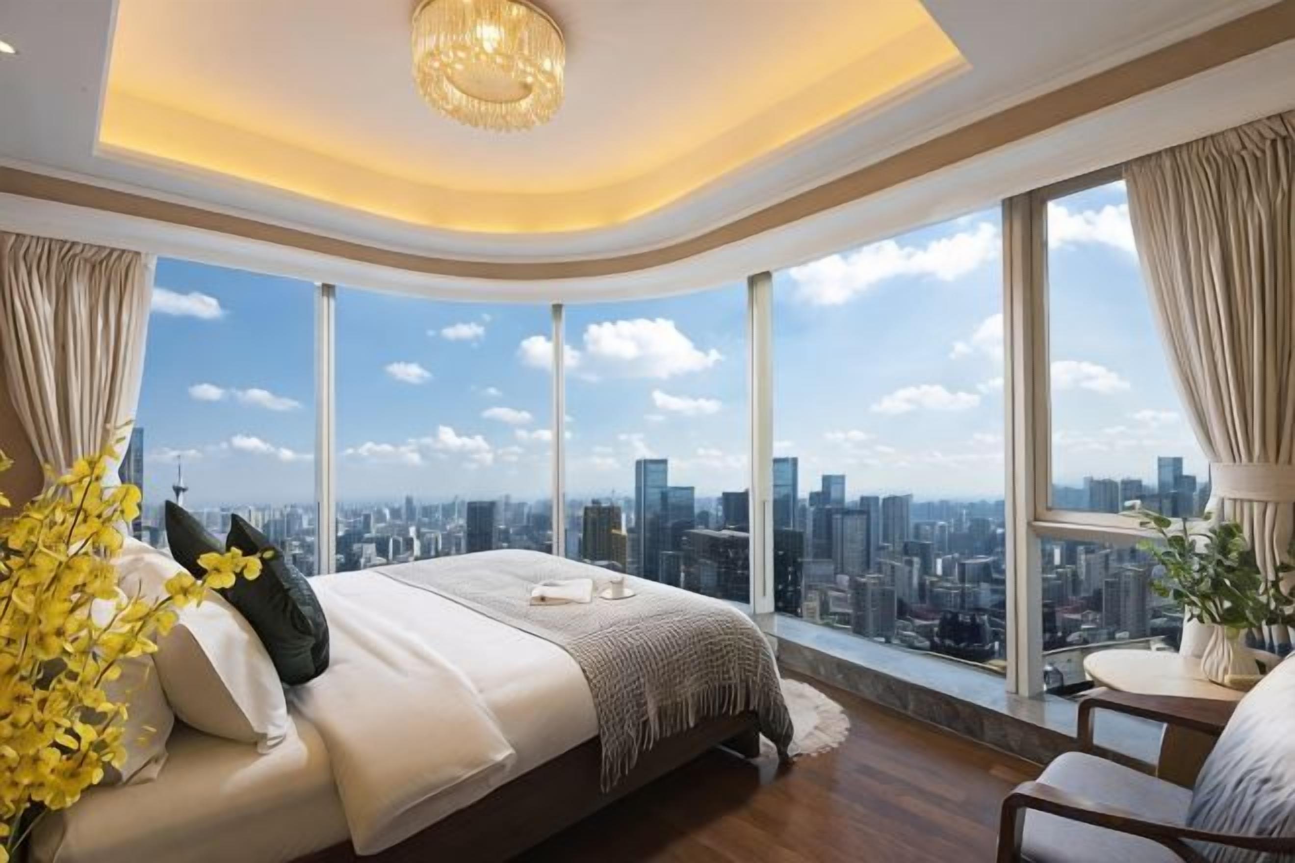 A bedroom with a large bed, a view of the city, and a chandelier.