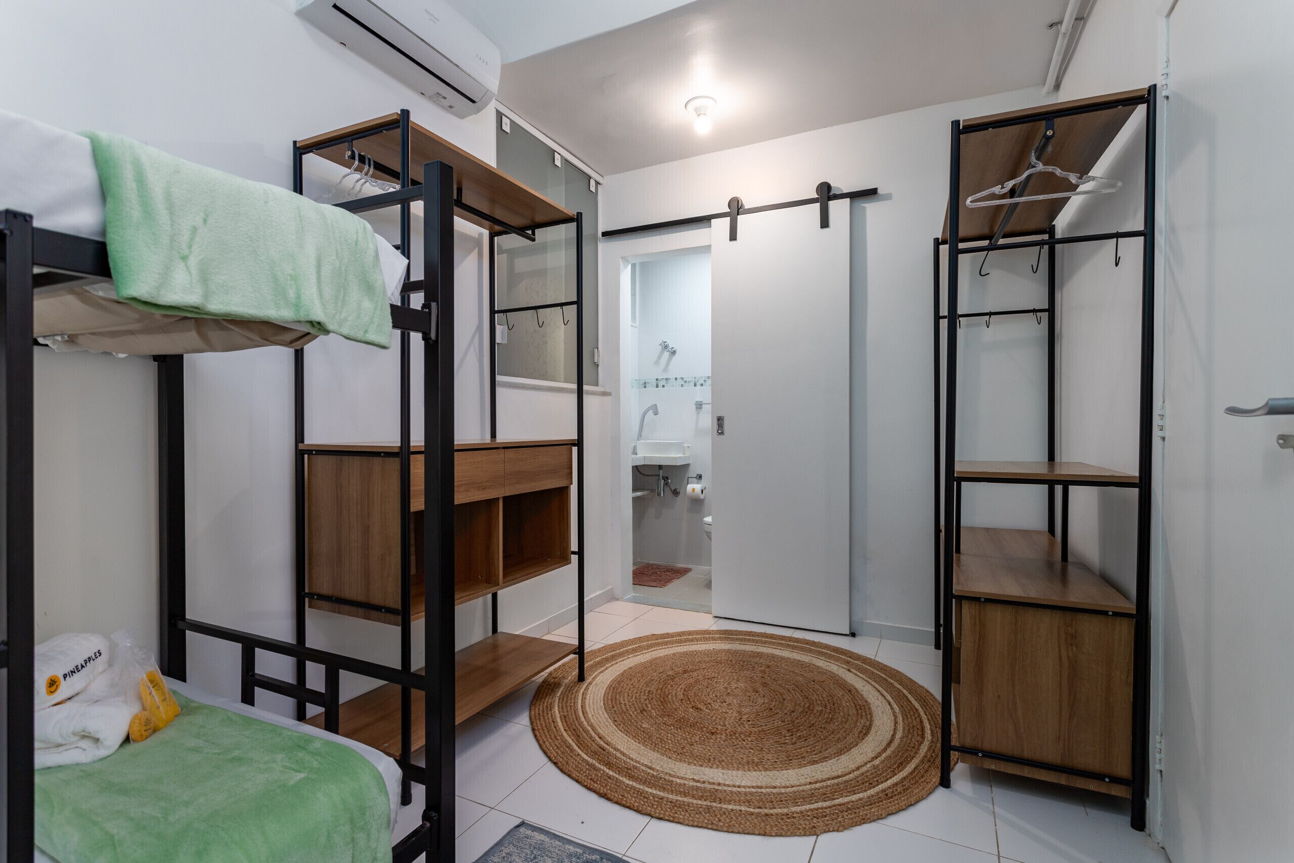 A compact room with bunk beds, a wardrobe, and a bathroom visible through an open door.