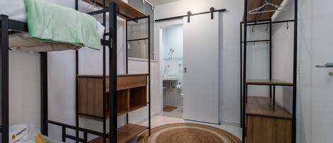 A compact room with bunk beds, a wardrobe, and a bathroom visible through an open door.