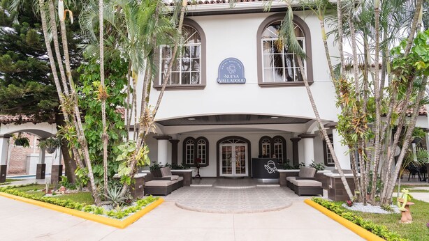 A hotel entrance with a covered patio, outdoor seating, and a sign indicating it is a hotel boutique. - Hotel Boutique Nueva Valladolid (Comayagua)