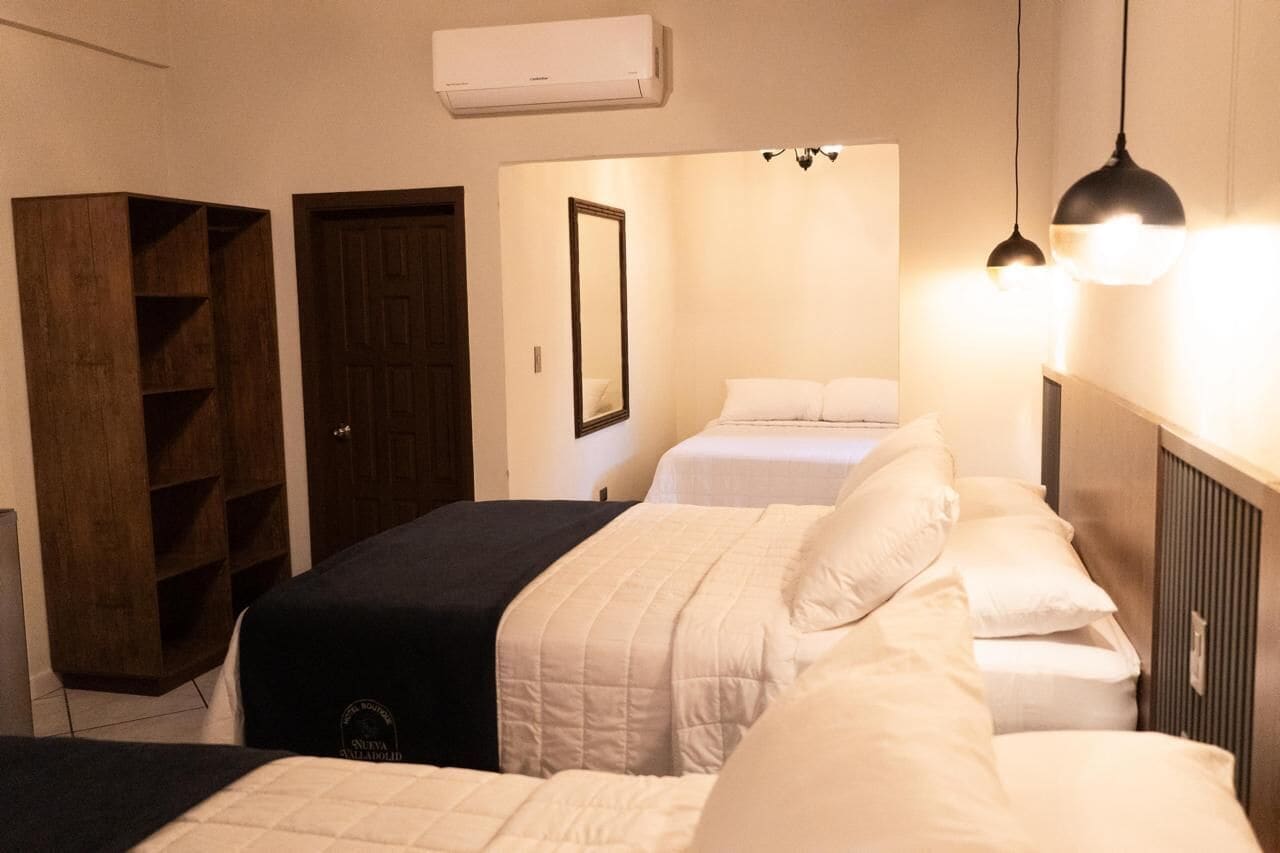 A hotel room with two beds, a wardrobe, a mirror, and a ceiling light fixture.