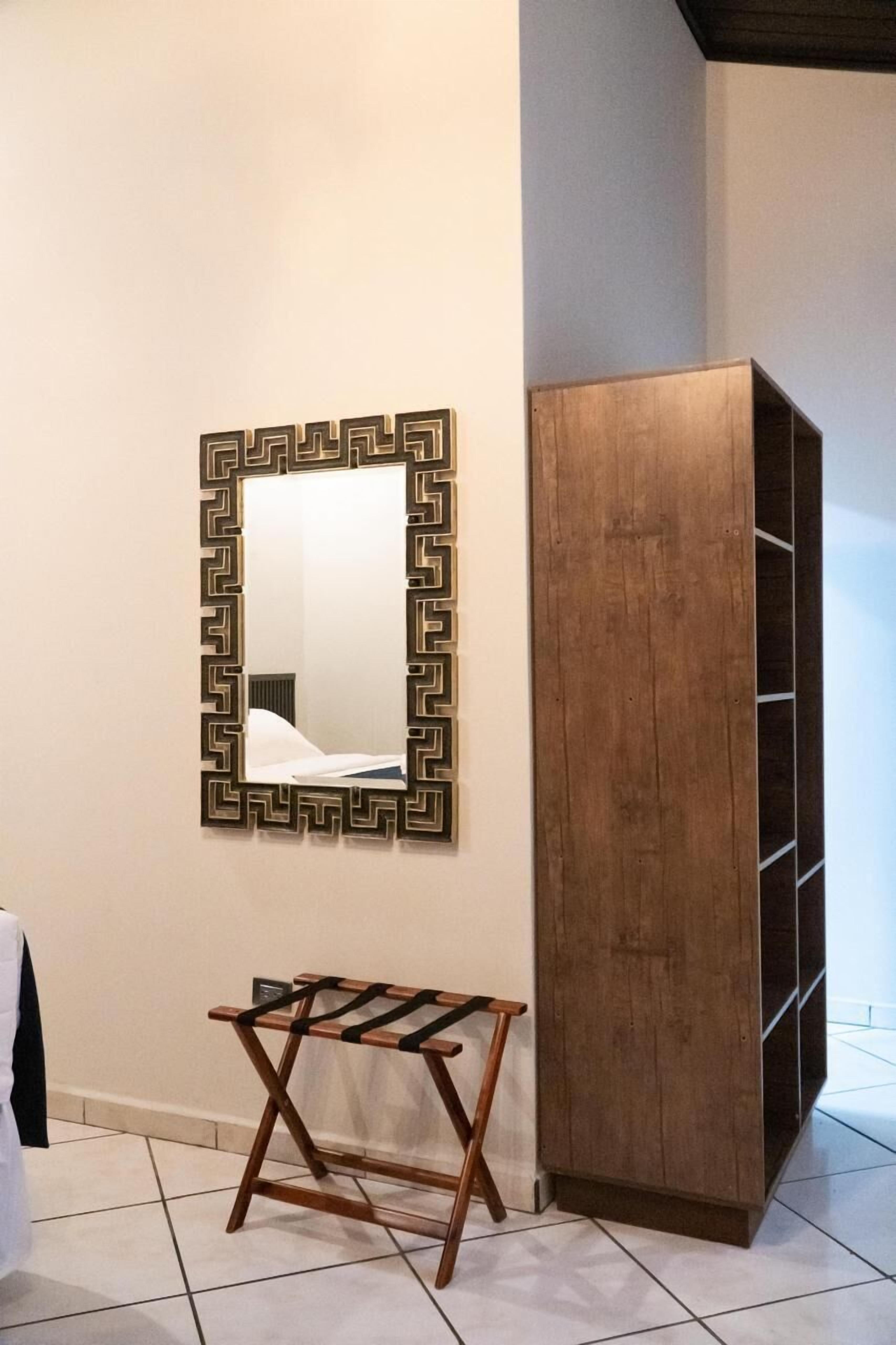 A room with a mirror, a wooden wardrobe, and a small wooden bench.