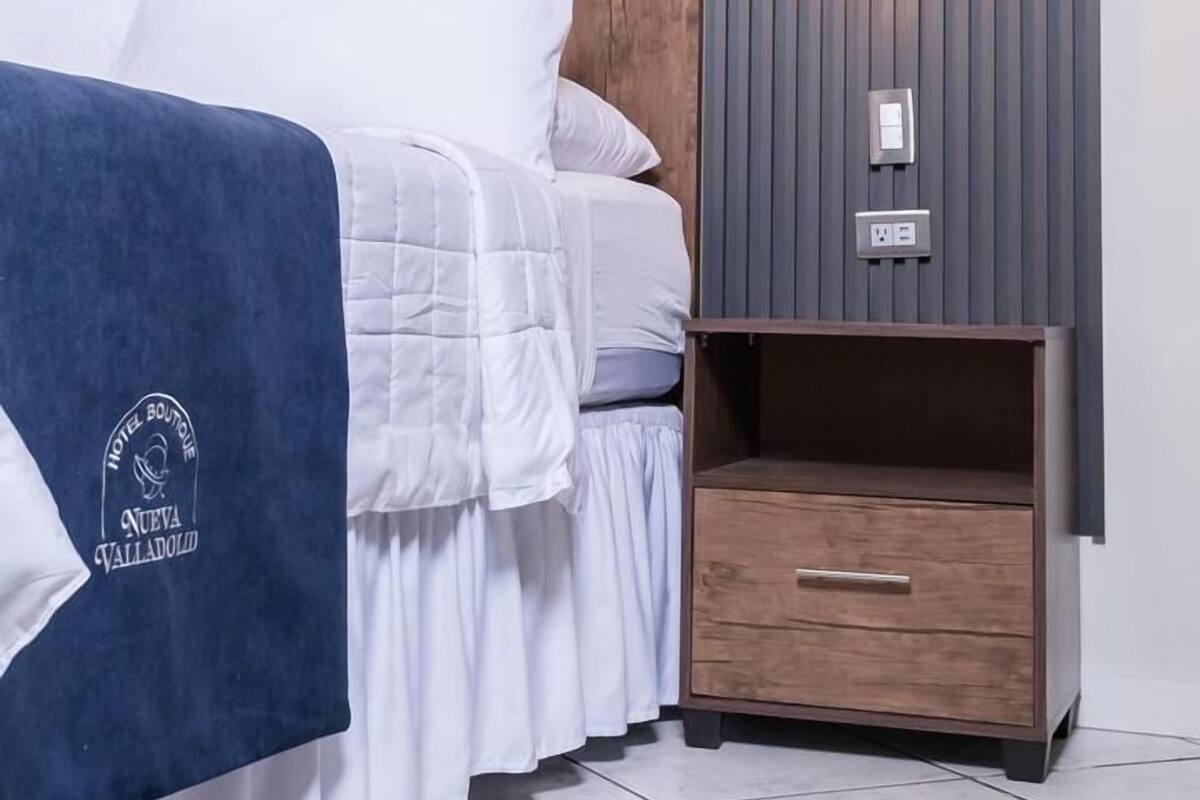 A modern bedroom with a bed, bedside table, and a hanging light fixture.