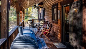 A wooden cabin with a covered porch, a barbecue grill, and a table with chairs. - 3 Irish Sons, 4BR, 3 BA  Log Cabin in the woods. (Nashville)