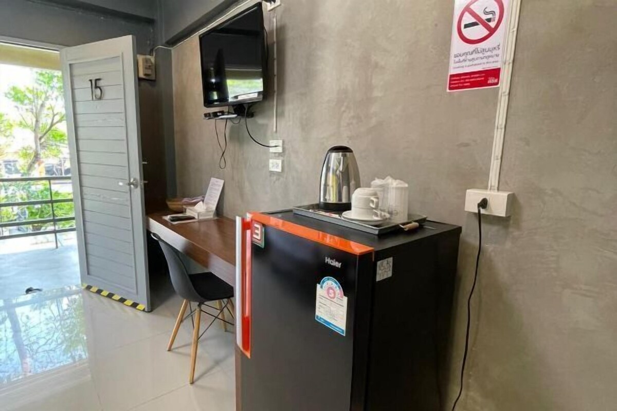 Un espace d’accueil d’hôtel comprenant un comptoir, une machine à café, un téléviseur et un panneau indiquant qu’il est interdit de fumer.