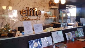 A reception desk with a marble wall, a sign reading "elite Phitsamukthon," and various informational displays. - Elite Residence Phitsanulok (Phitsanulok)