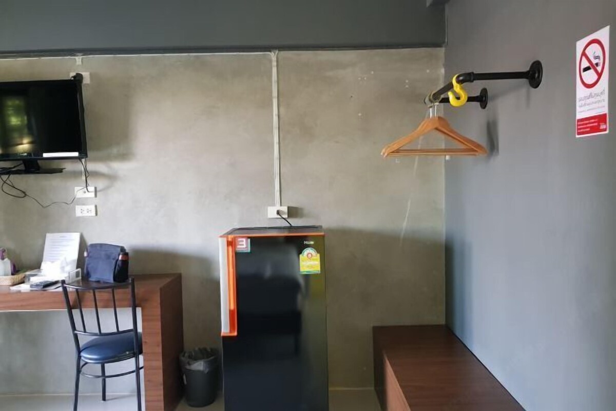 Une pièce comprenant un bureau, une chaise et un réfrigérateur noir.