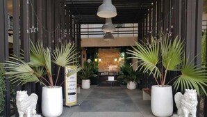 A hotel entrance with a check-in desk, potted plants, and two lion statues. - Elite Residence Phitsanulok (Phitsanulok)
