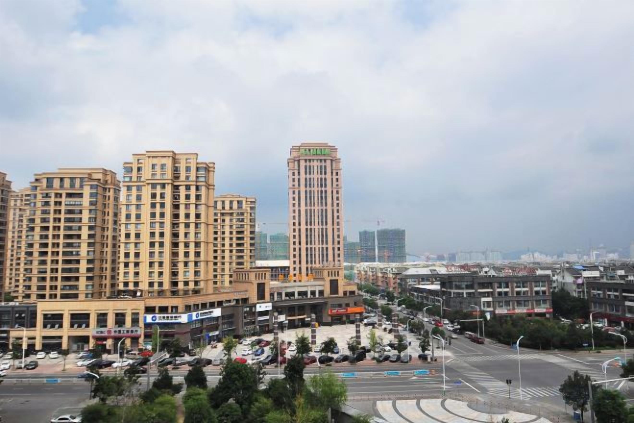 A cityscape with high-rise buildings, a roundabout, and a clear sky.