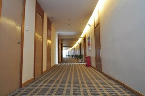 A hotel corridor with doors on both sides, a patterned carpet, and a red trash bin. - Mingshi Hotel Yuyao Wanda Plaza Branch (Yuyao)