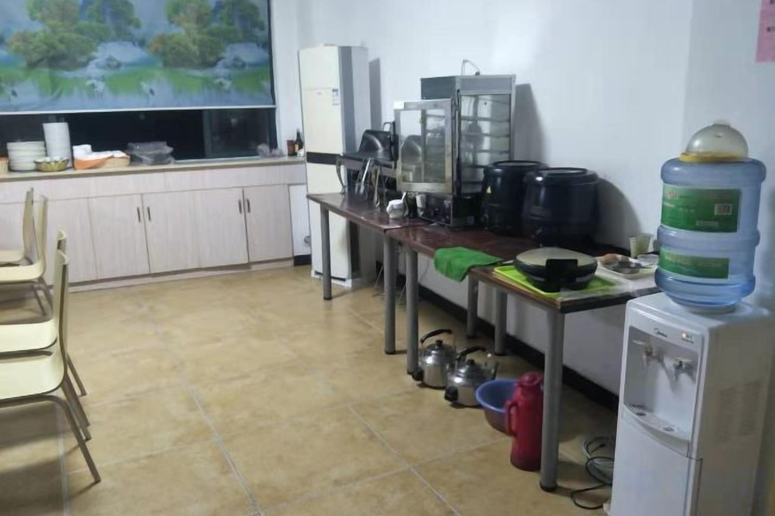 Una cucina con dispenser d'acqua, macchina del caffè e frigorifero.