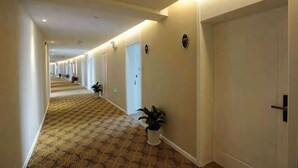 A hotel corridor with carpeted flooring, doors, and potted plants. - Mingshi Hotel Yuyao Wanda Plaza Branch (Yuyao)