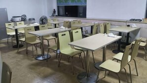 A classroom with tables and chairs, a projector screen, and a window with a view. - Mingshi Hotel Yuyao Wanda Plaza Branch (Yuyao)