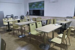 Ein Klassenzimmer mit Tischen, Stühlen, einer Projektionsfläche und einem Fenster mit Blick.