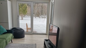 Una habitación de hotel moderna con una cama, un escritorio, una televisión y vistas a un área exterior nevada.