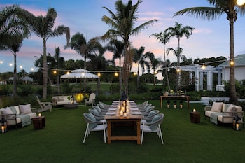 A resort with a large pool, multiple balconies, and palm trees. at The Belgrove Resort & Spa, West Palm Beach, Autograph Collection