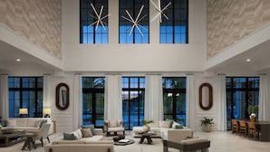 A spacious living room with multiple seating options, large windows, and modern decor. - The Belgrove Resort & Spa, West Palm Beach, Autograph Collection (West Palm Beach)