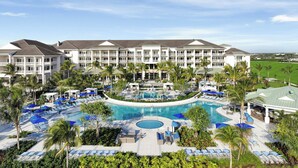 A resort with a large pool, multiple balconies, and palm trees. - The Belgrove Resort & Spa, West Palm Beach, Autograph Collection (West Palm Beach)