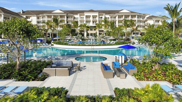 A resort with a central pool, lounge areas, and a multi-story building with balconies. - The Belgrove Resort & Spa, West Palm Beach, Autograph Collection (West Palm Beach)