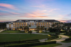 Een groot hotel met meerdere verdiepingen, een verzorgd gazon en een gebogen oprit.