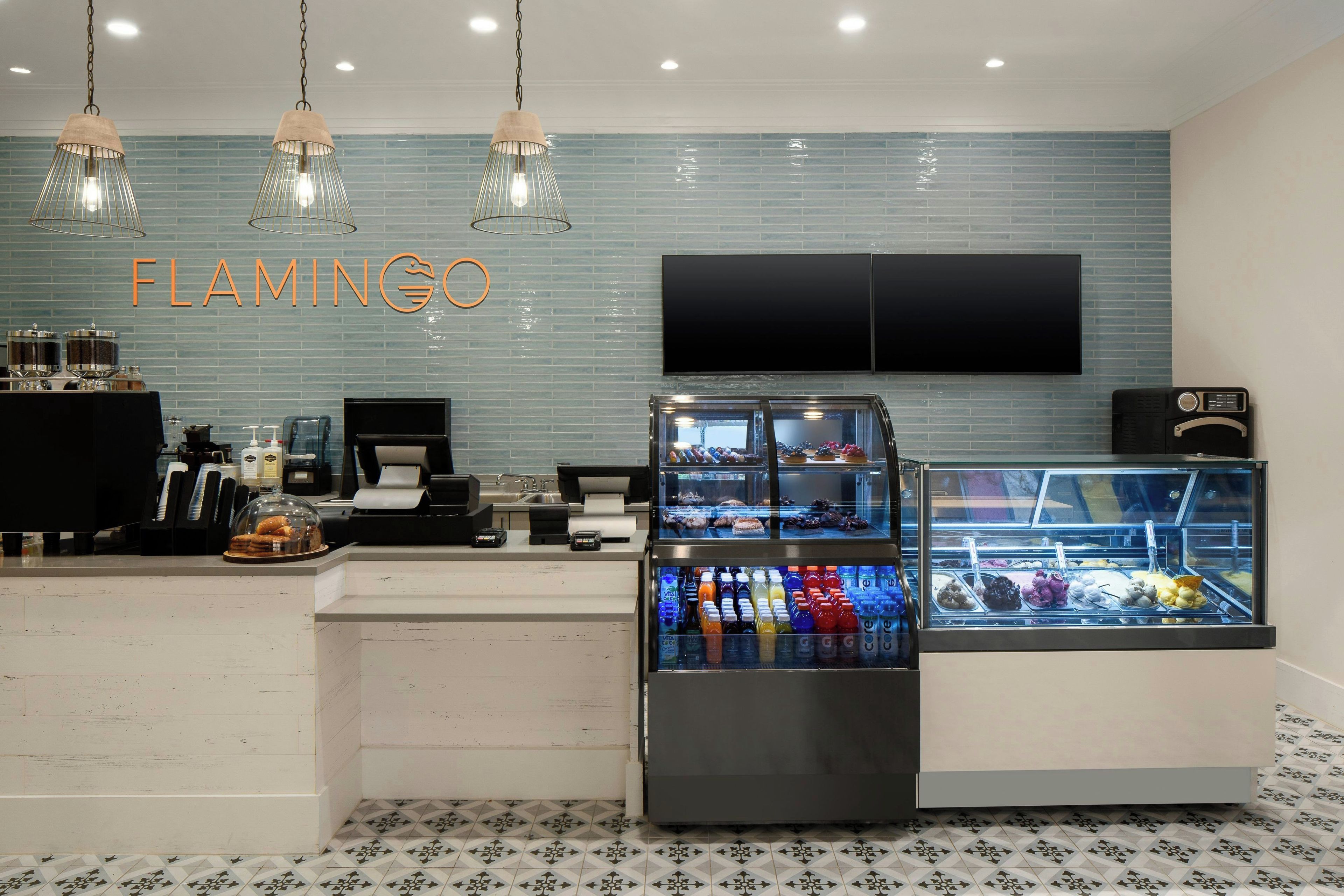 Interior de restaurante com balcão, vitrine de bebidas, televisão e parede com o nome 'FLAMINGO'.