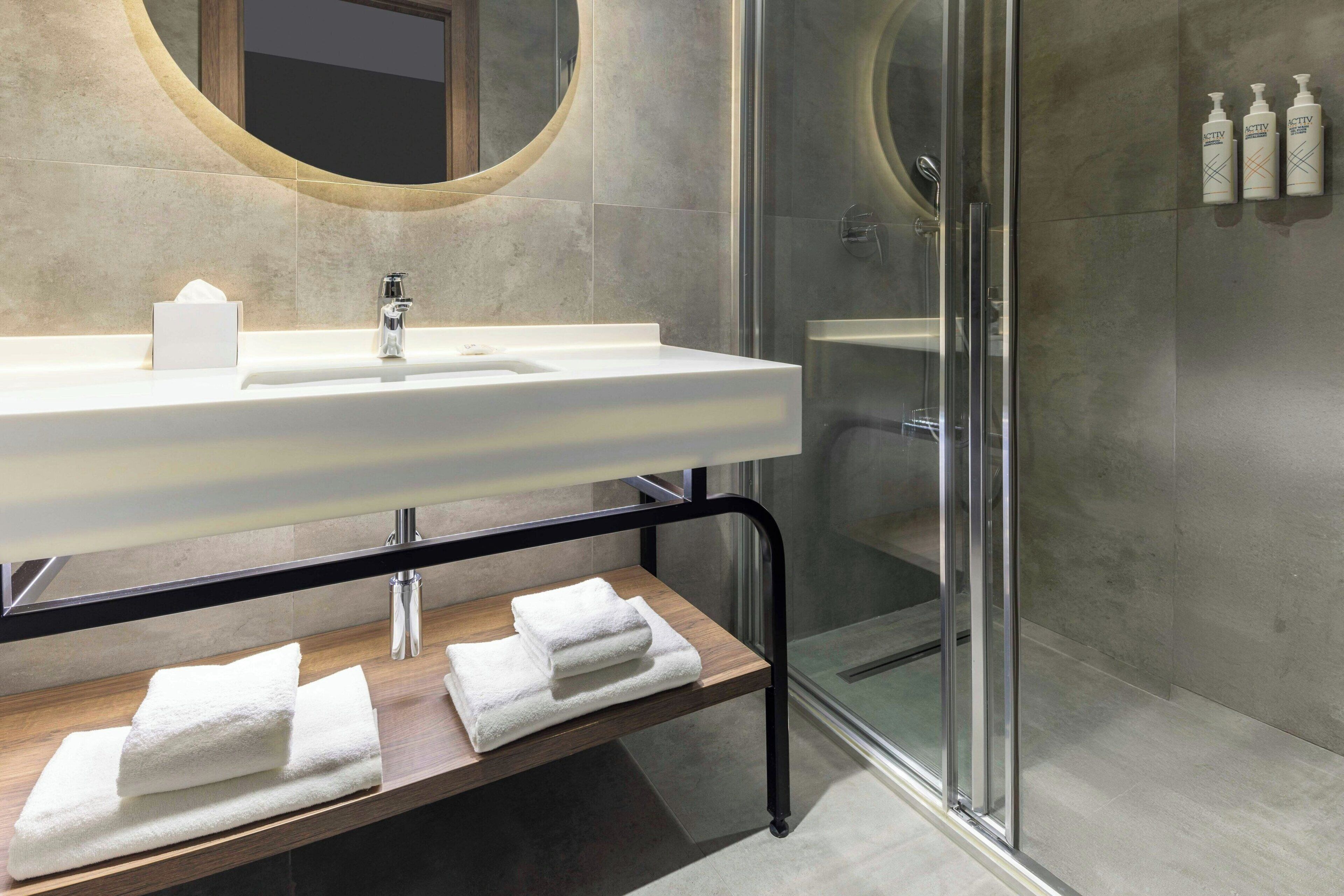 Un baño moderno con un lavamanos grande, un espejo y una cabina de ducha de vidrio.