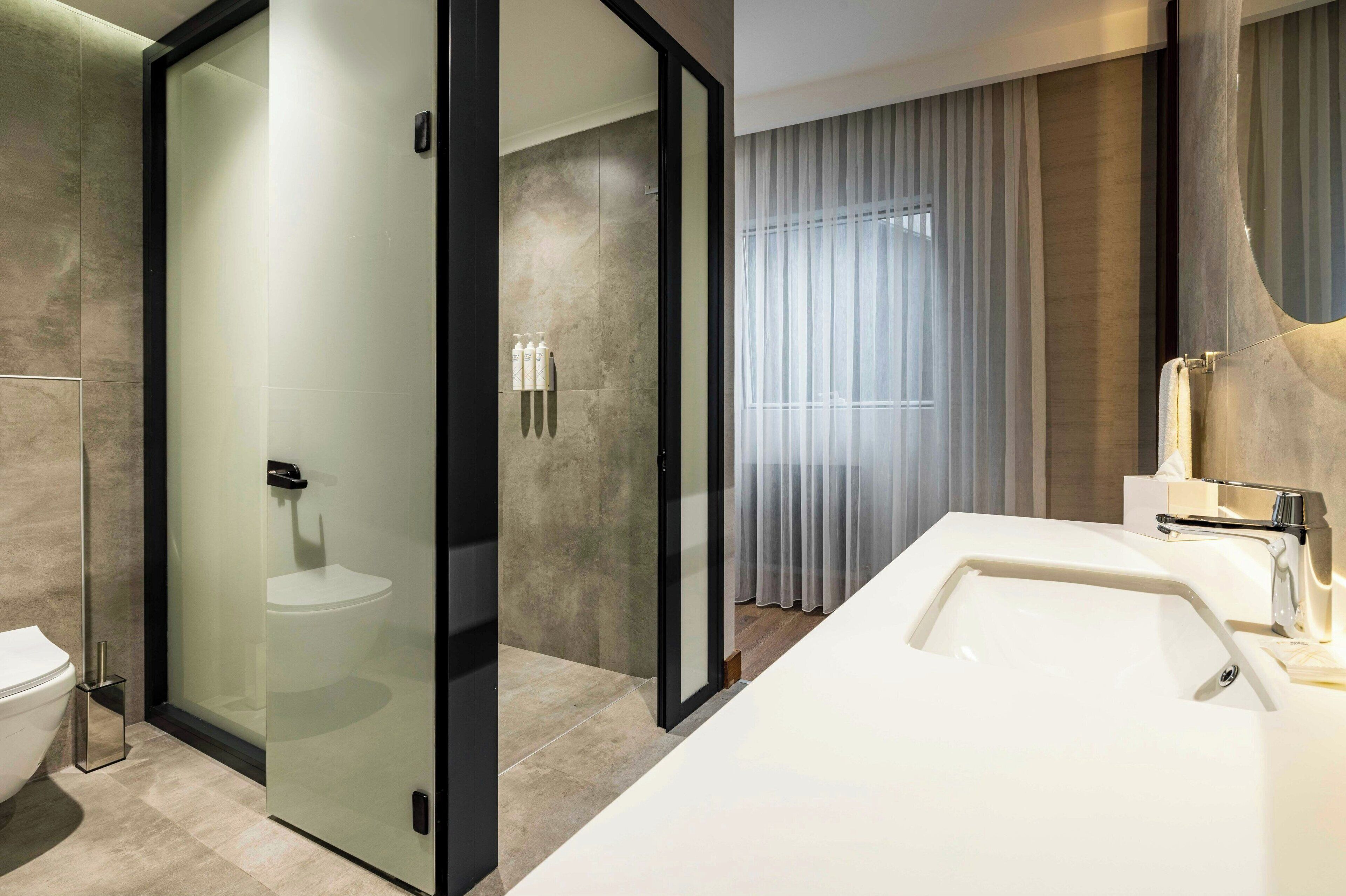 A modern bathroom with a glass-enclosed shower, a white sink, and a toilet.