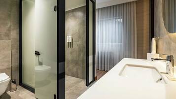 A modern bathroom with a glass-enclosed shower, a white sink, and a toilet.