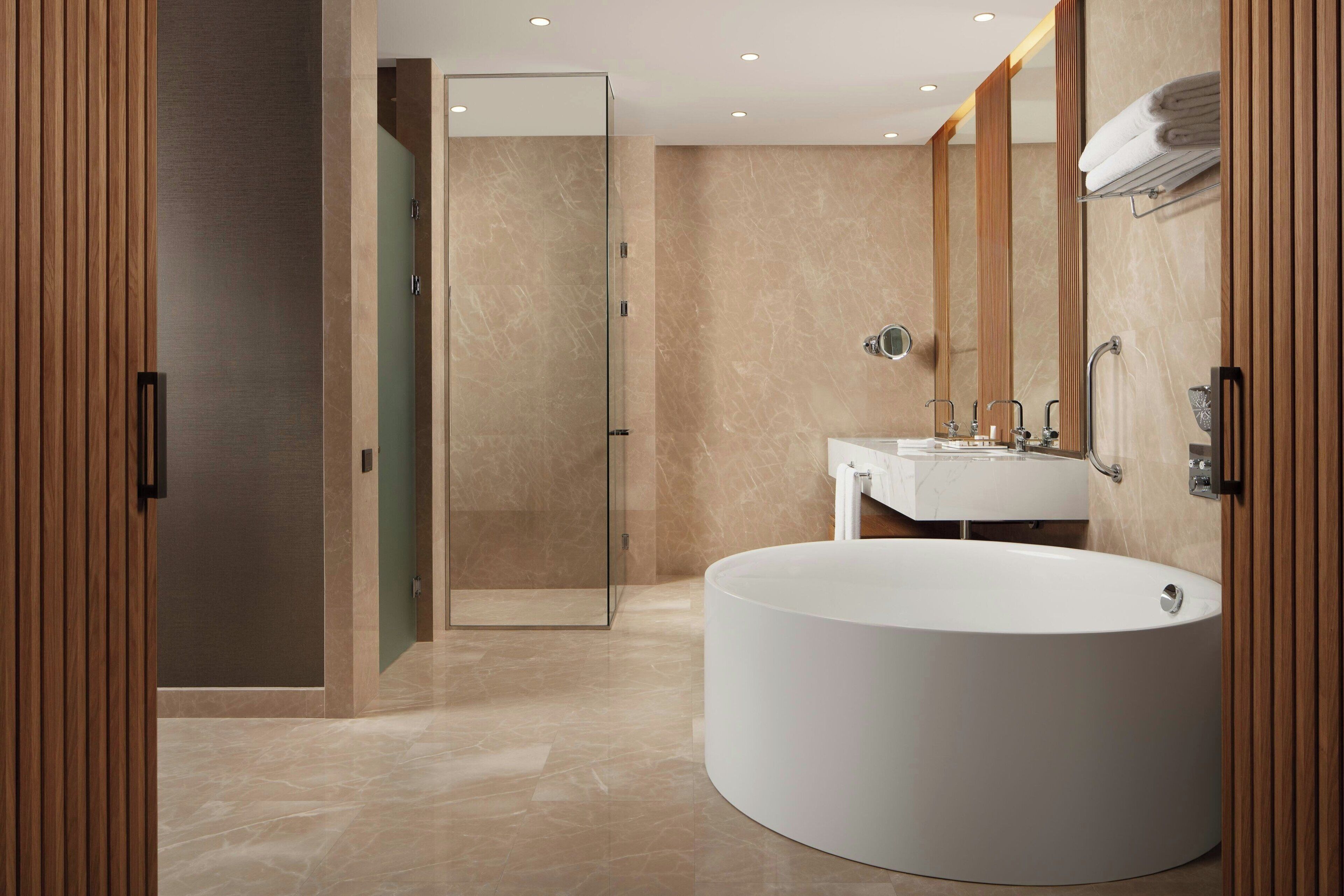 A modern bathroom with a large bathtub, a glass-enclosed shower, and a vanity with a mirror.