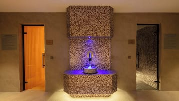 A spa area with a mosaic wall, a water feature, and two doors labeled "SAUNA USE" and "STEAM ROOM USE".