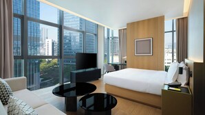 Une chambre d’hôtel moderne avec un grand lit, un canapé, une télévision et un bureau.