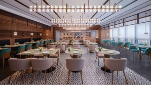 Un vaste espace dédié à la salle à manger, avec de nombreuses tables et chaises, un lustre moderne et de grandes fenêtres laissant entrer la lumière naturelle.