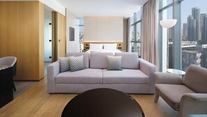 Une chambre d’hôtel moderne dotée d’une grande fenêtre, d’un canapé, d’un fauteuil et d’une table ronde.