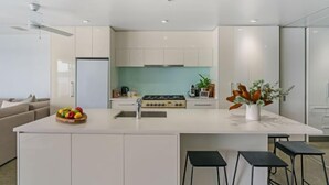 A modern kitchen with a central island, white cabinetry, and a stainless steel stove.