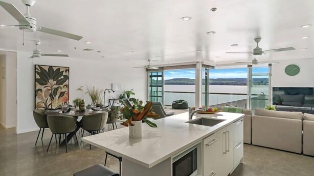 A modern kitchen with a large island, dining area, and a view of the water.