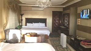 Ein Hotelzimmer mit einem großen Bett, einem Fernseher, einer Kristallleuchtre und einem Holzschrank.