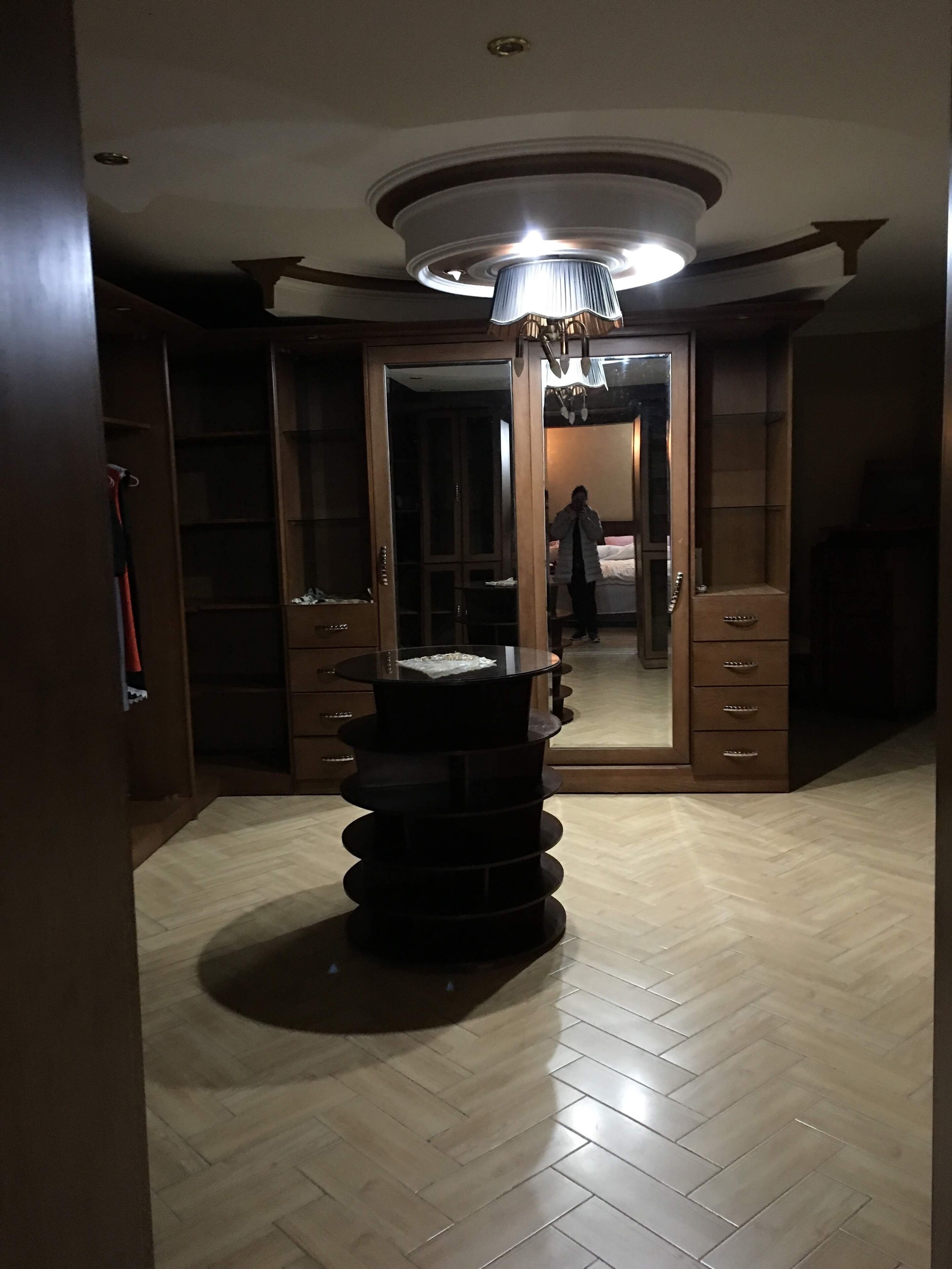 A room with a large mirror, a circular ceiling light, and a wooden floor.