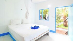 A bedroom with a bed, a mosquito net, a door leading to a garden, and a framed picture on the wall. - Isara Lanta Beach Resort (Koh Lanta)