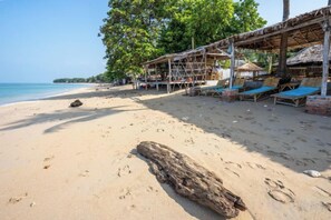 A beach with sun loungers and a wooden structure, likely a beach hut or bar, with a clear view of the ocean. - Isara Lanta Beach Resort (Koh Lanta)