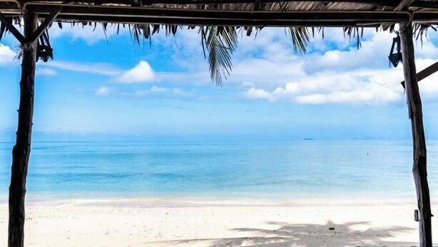 A beach view with a wooden structure and a clear sky. - Isara Lanta Beach Resort (Koh Lanta)