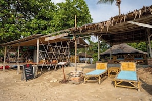 A beachside structure with a thatched roof, wooden seating, and a signboard. - Isara Lanta Beach Resort (Koh Lanta)
