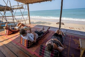 A wooden deck with people relaxing on mats by the ocean. - Isara Lanta Beach Resort (Koh Lanta)