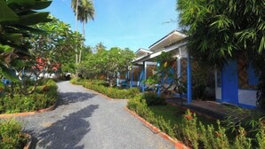 A pathway flanked by lush greenery and blue-framed buildings, suggesting a tropical resort setting. - Isara Lanta Beach Resort (Koh Lanta)