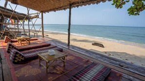 A beachside seating area with wooden furniture and colorful mats. - Isara Lanta Beach Resort (Koh Lanta)