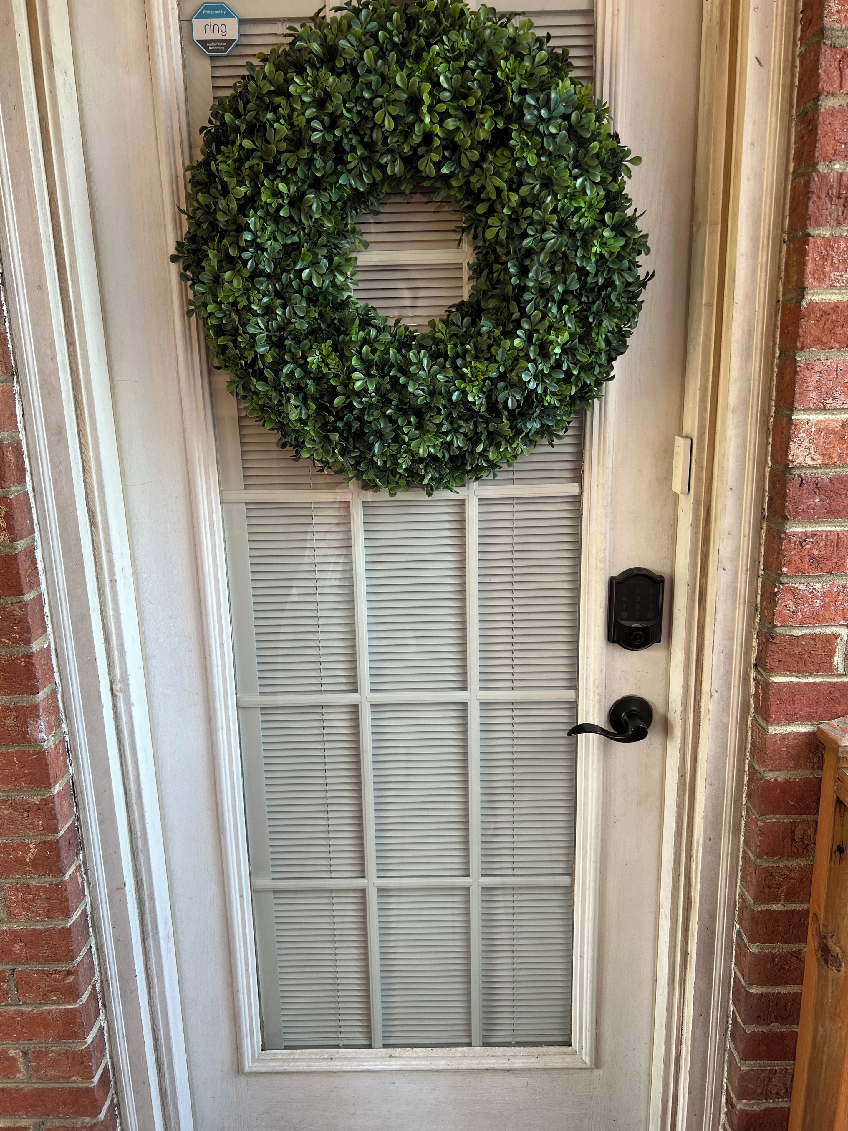 A door with a green wreath, a mailbox, and a doorbell.