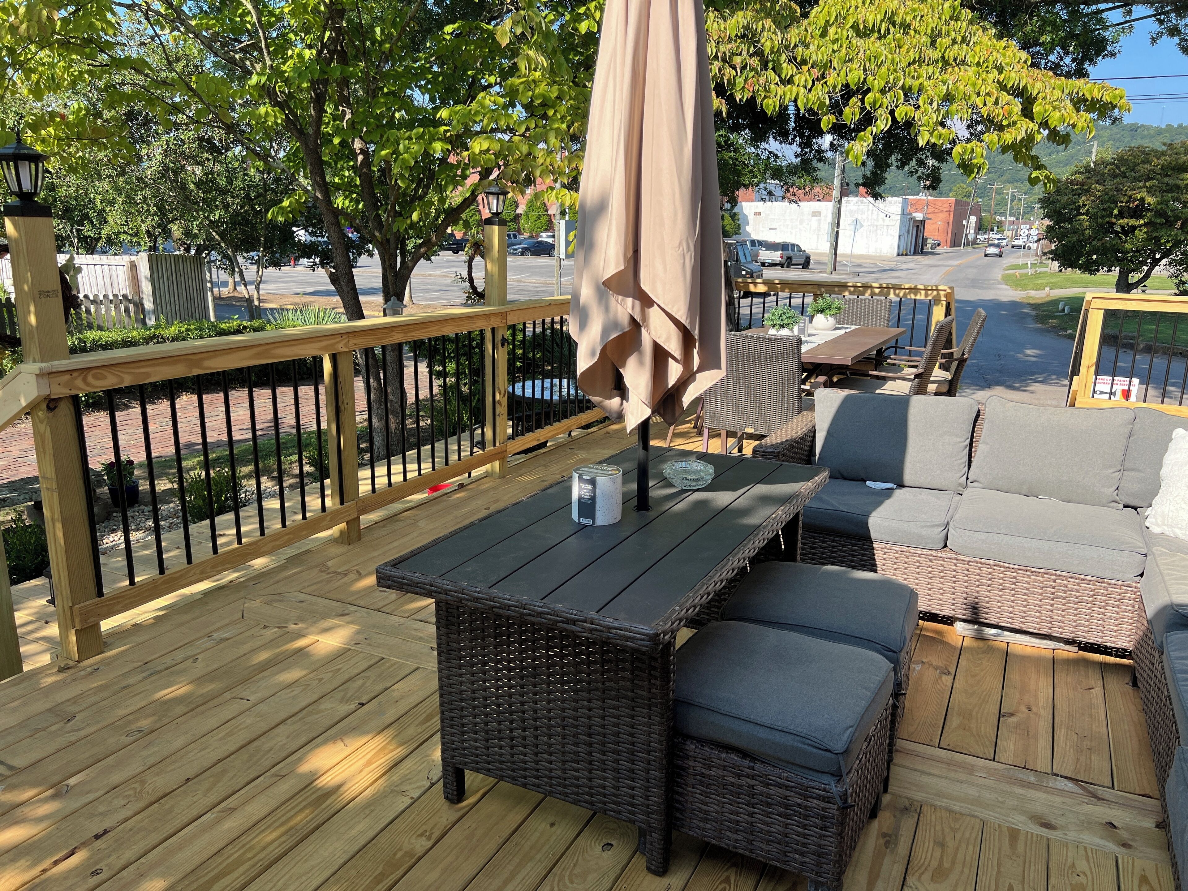 A wooden deck with outdoor furniture, including a table and a sofa, surrounded by a wooden railing.